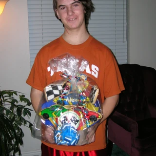 Alex in his Texas shirt holding a gift basket