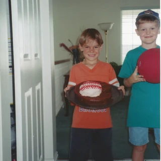 Alex holding a baseball birthday cake with Landon