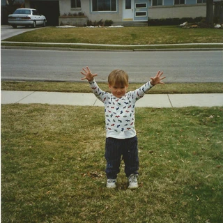 Alex holding his arms up as a toddler
