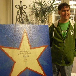 Alex standing by the Make A Wish Welcome sign