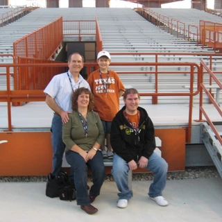 Alex, mom, dad, and Josh sitting by the field