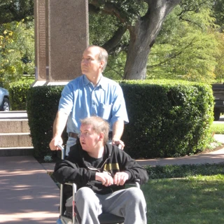 Dad pushing Alex in a wheelchair at the Alamo