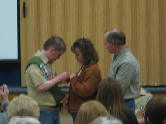 Alex at his eagle court of honor pinning a badge on Mom