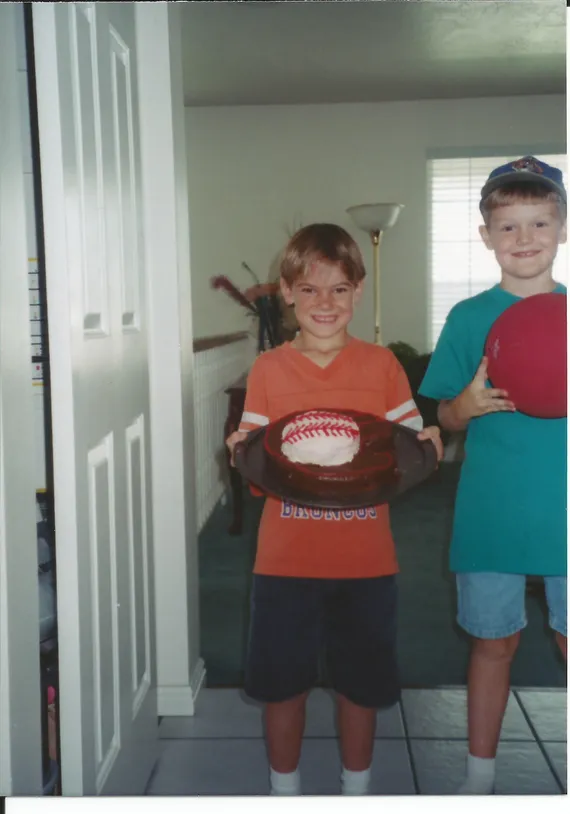 Alex holding a baseball birthday cake with Landon