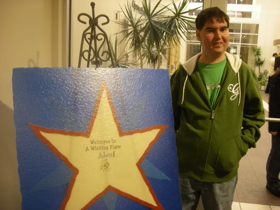 Alex standing by the Make A Wish Welcome sign