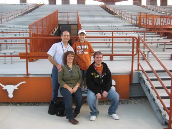 Alex, mom, dad, and Josh sitting by the field