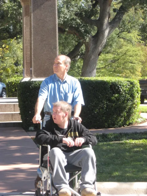 Dad pushing Alex in a wheelchair at the Alamo